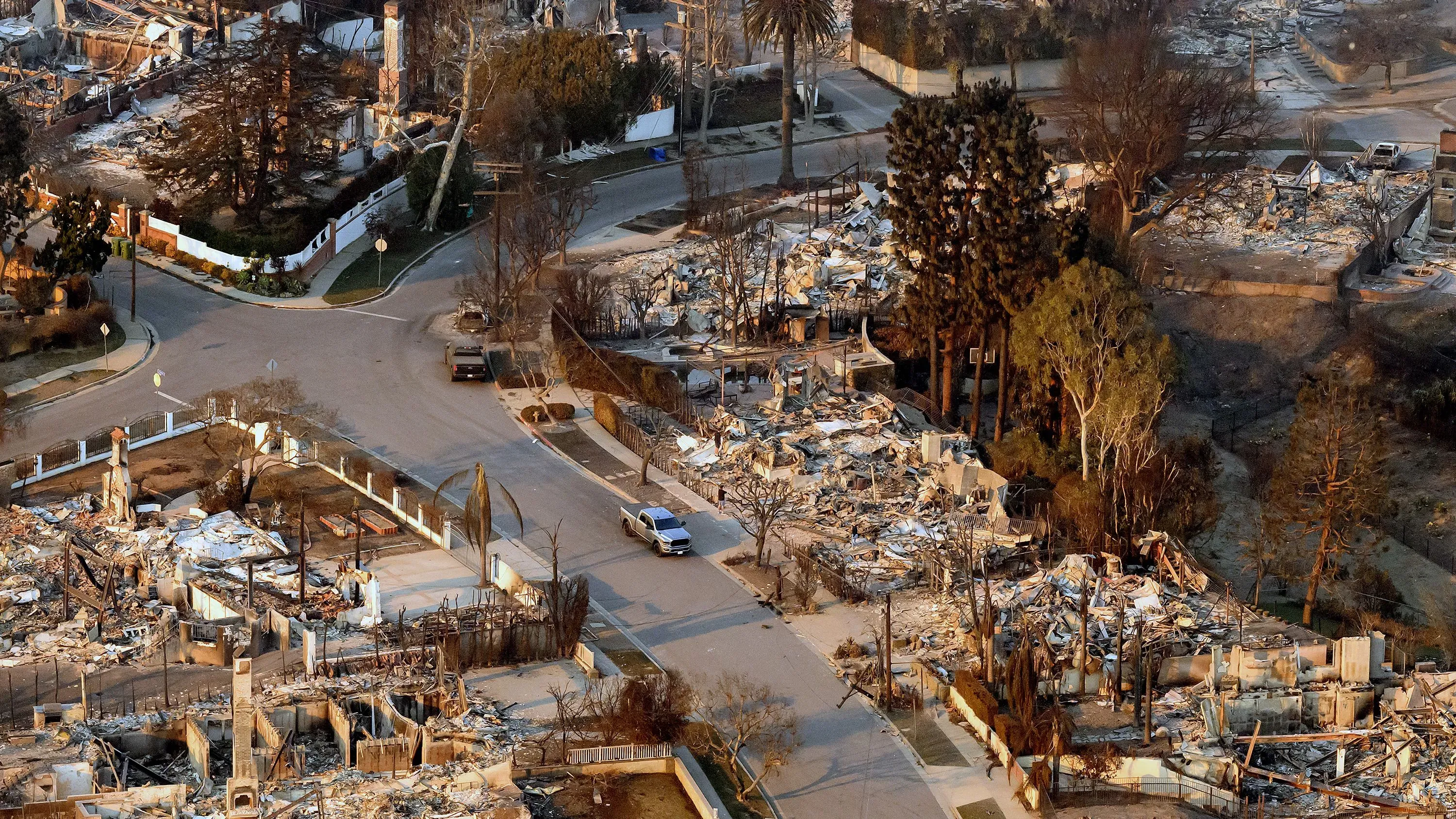 صورة جوية لمنطقة دمرتها حرائق الغابات في كاليفورنيا، تظهر المنازل المحترقة والخراب في الشوارع، مما يعكس أزمة التأمين المتزايدة.