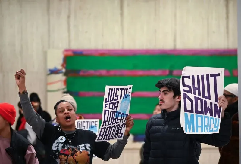 محتجون يحملون لافتات تطالب بالعدالة لروبرت بروكس وإغلاق إصلاحية مارسي، تعبيرًا عن الغضب بعد وفاته نتيجة العنف في السجن.