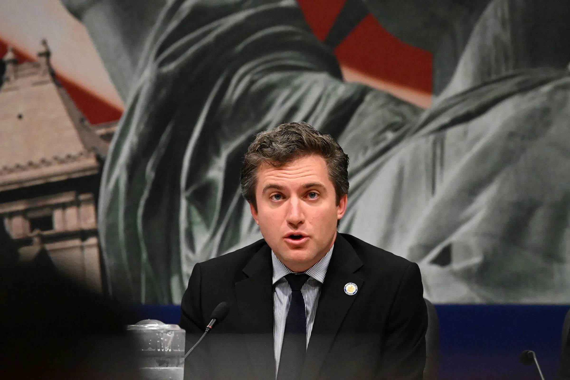 جيمس سكوفيس يتحدث في مؤتمر صحفي حول اقتراحه لنقل الانتخابات التمهيدية الرئاسية في نيويورك إلى يوم الثلاثاء الكبير، مع خلفية تمثال الحرية.