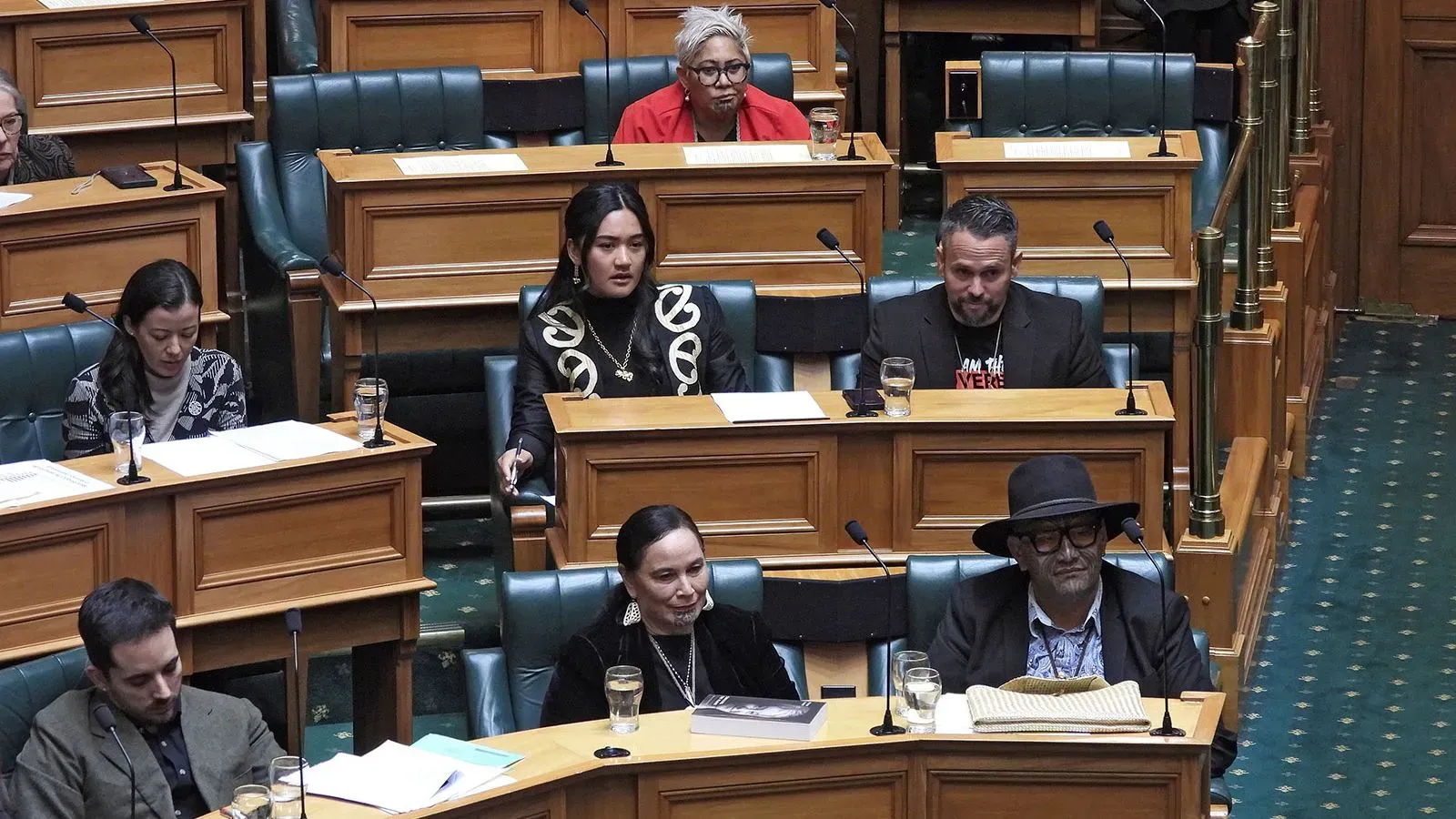 مشرعون نيوزيلنديون في البرلمان خلال نقاش حول عقوبات إيقاف بسبب أداء رقصة الهاكا الماورية، مع تباين في ردود الفعل بين الأعضاء.