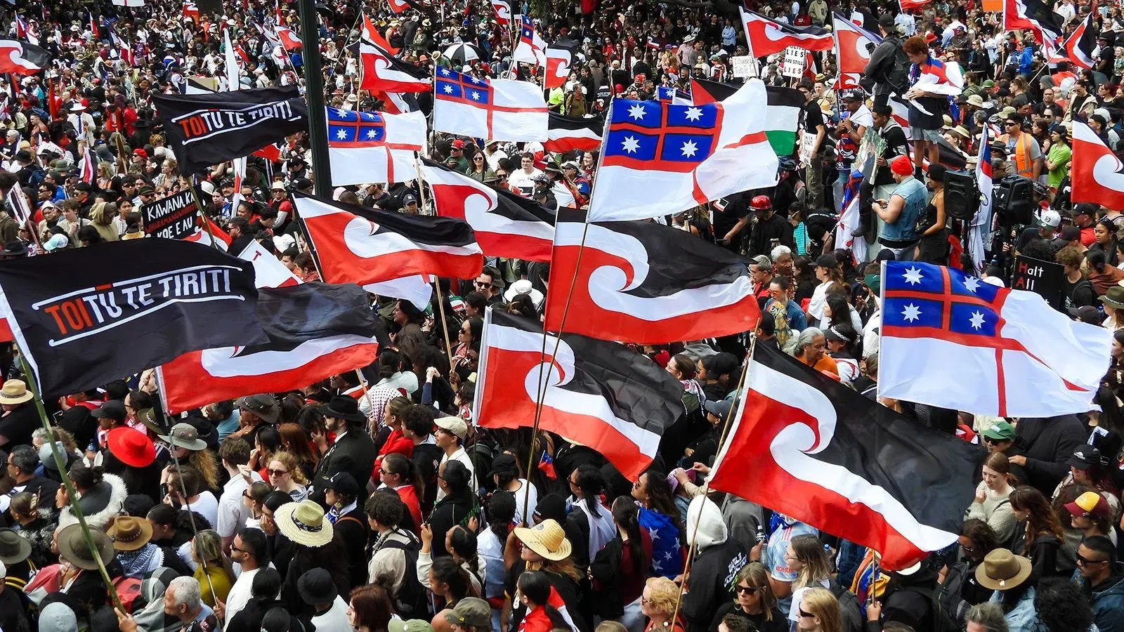 مظاهرة حاشدة لمجتمع الماوري في نيوزيلندا، حيث ترفرف أعلام تحمل شعار "توتو تي تيريتى"، تعبيرًا عن الاحتجاج ضد مشروع قانون يهدد حقوقهم.