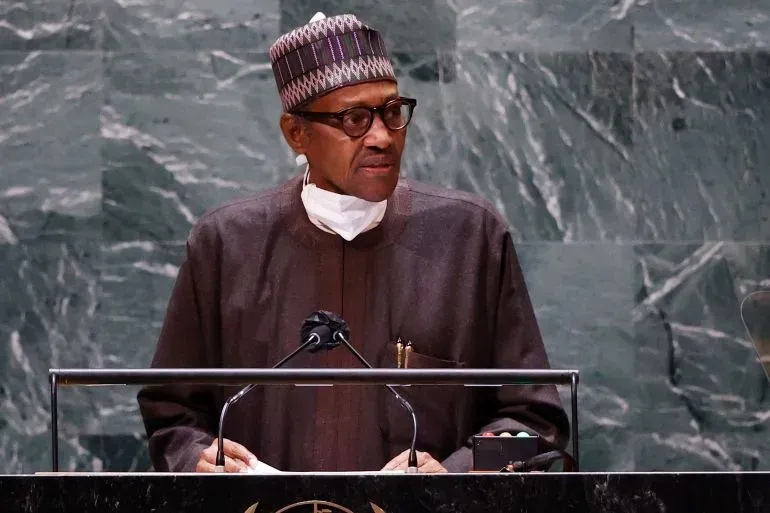 محمد بخاري، الرئيس النيجيري السابق، يلقي خطابًا في الأمم المتحدة، مرتديًا زيًا تقليديًا ونظارات، مع خلفية من الحجر الأخضر.