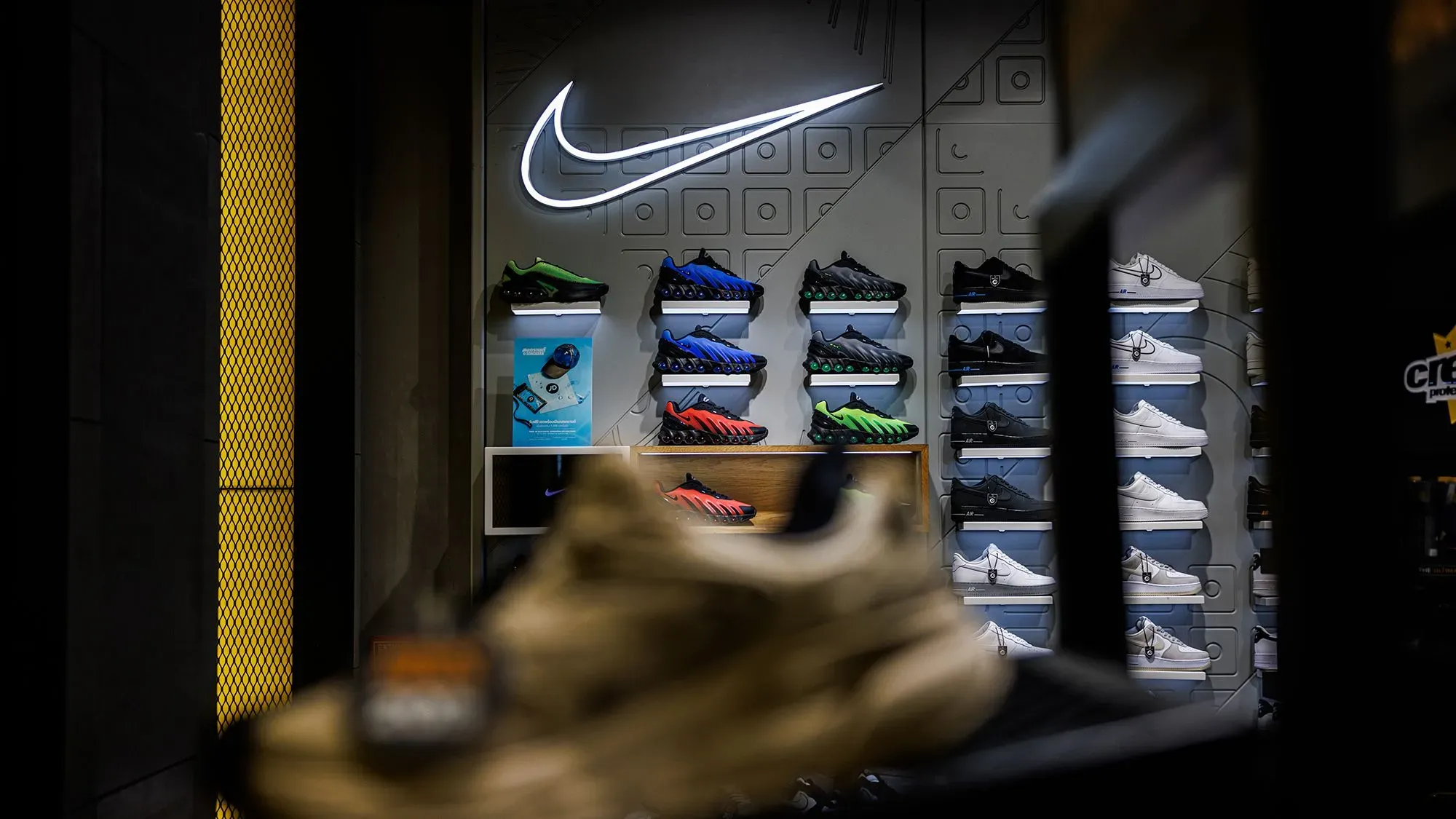 واجهة متجر نايكي تعرض مجموعة متنوعة من الأحذية الرياضية، مع شعار نايكي مضيء، تعكس عودة الشركة إلى أمازون واستراتيجياتها الجديدة في السوق.