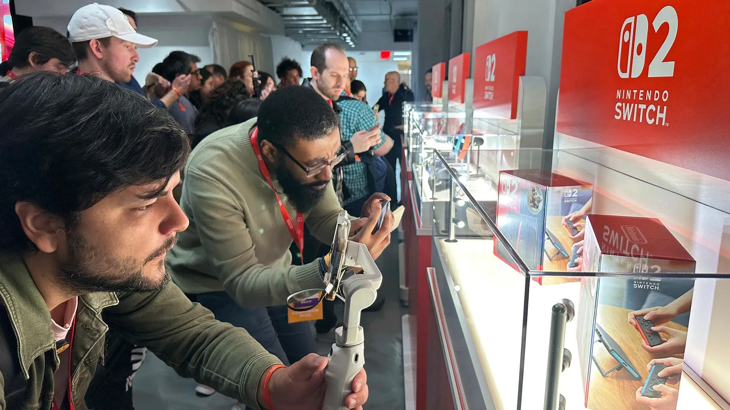 جمهور يتفاعل مع جهاز Nintendo Switch 2 الجديد في حدث إطلاق، مع عرض الجهاز في زجاجات عرض مضاءة.
