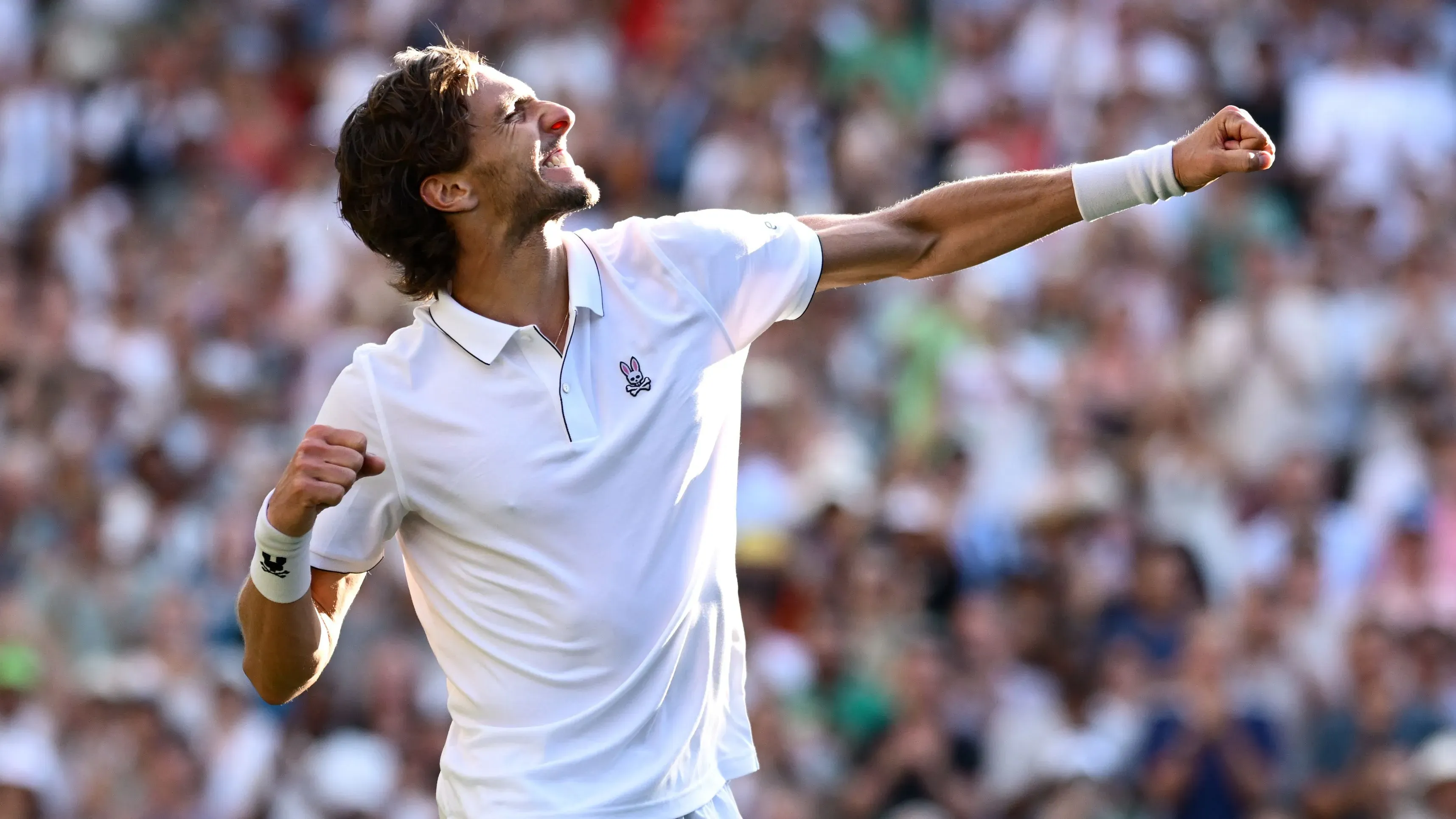 آرثر ريندركنيش يحتفل بفوزه المفاجئ على ألكسندر زفيريف في ويمبلدون، مع تعبير عن الفرح وسط جمهور متحمس.