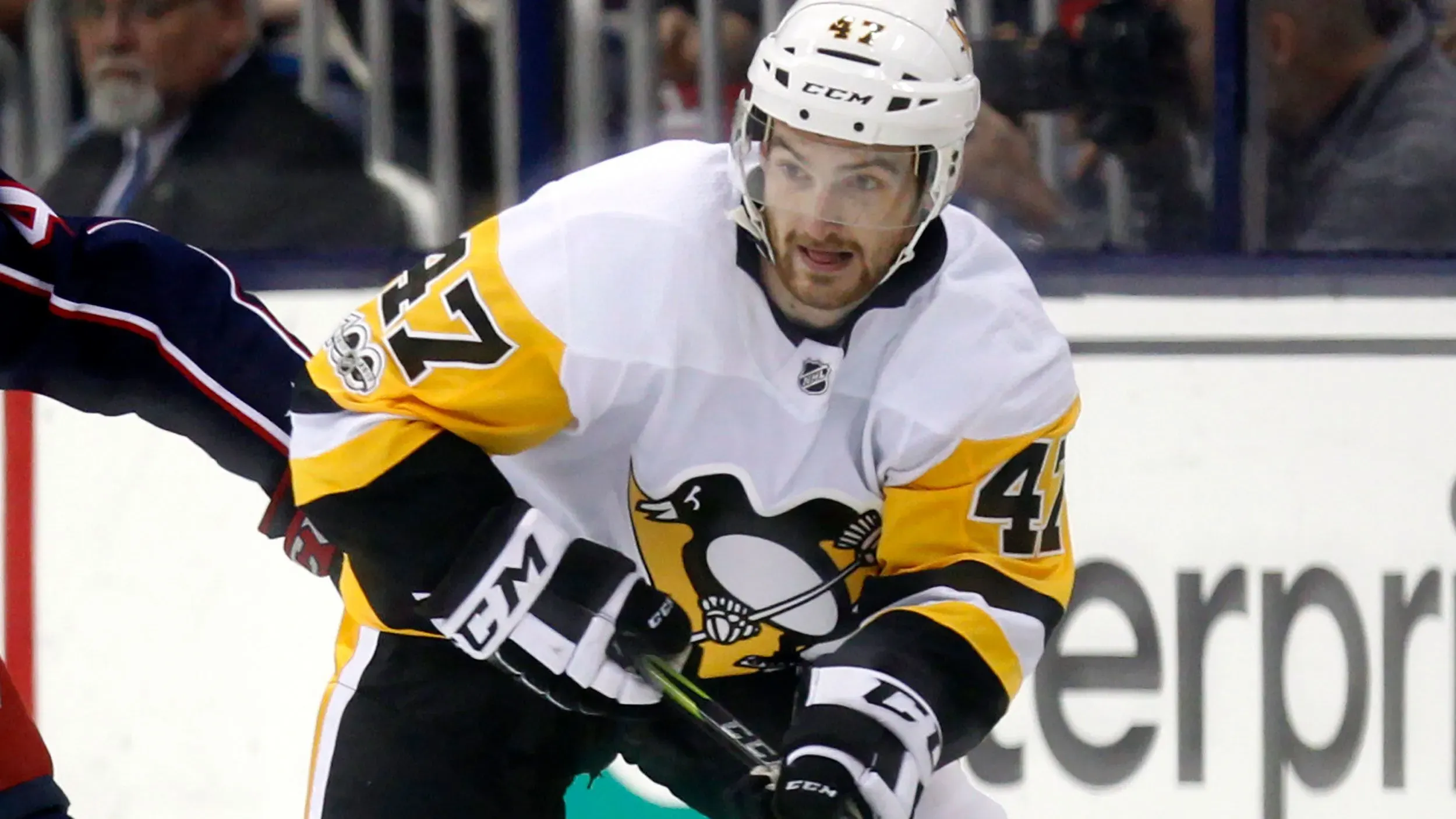 لاعب هوكي الجليد آدم جونسون يرتدي زي فريقه بينما يتنافس في مباراة، حيث توفي بعد إصابة خطيرة في الرقبة خلال مباراة في 2023.