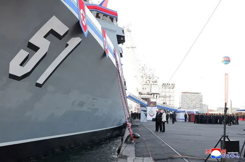 المدمرة الكورية الشمالية رقم 51 راسية على الرصيف، مع وجود عدد من الأشخاص في الخلفية، تعكس جهود التحديث البحري للبلاد.