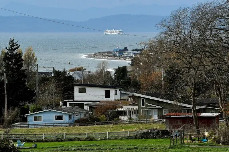 منظر طبيعي يضم منازل قريبة من بحيرة، مع سفينة عابرة في الخلفية، يعكس تأثير السياحة الكندية على منطقة نورث كونتري.