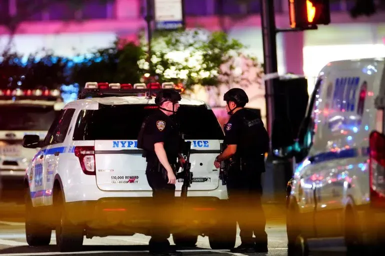 شرطة نيويورك تتجمع حول سيارة دورية بعد إطلاق نار في مانهاتن، حيث قُتل أربعة أشخاص، بما في ذلك ضابط شرطة.