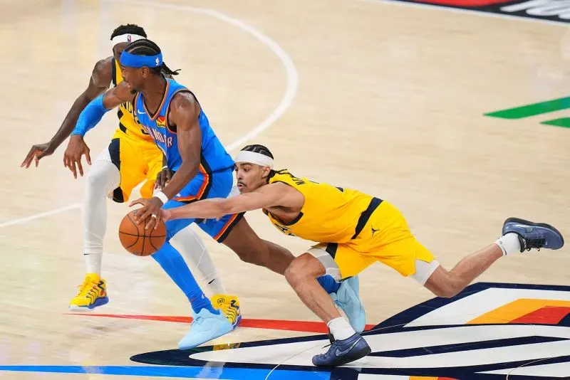 شاي جيلجوس-أليكساندر يحاول السيطرة على الكرة وسط منافسة شرسة من لاعبي إنديانا بيسرز، في مباراة مثيرة بدوري NBA.