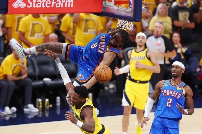 لاعب أوكلاهوما سيتي ثاندر يحقق سلة مذهلة فوق لاعب إنديانا بيسرز، مع تفاعل حماسي من الجمهور في الخلفية.