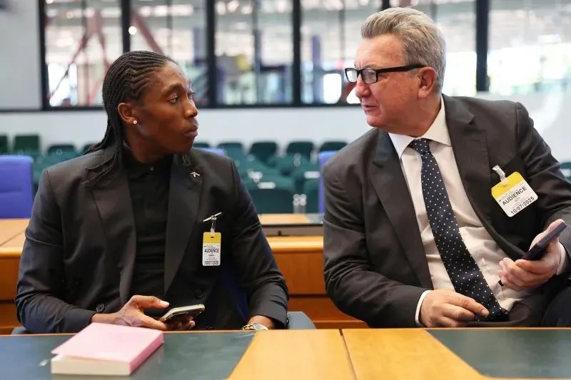 كاستر سيمينيا تجلس مع محاميها في قاعة المحكمة، تعبيرات وجههما تعكس أهمية القضية المتعلقة بحقوق الرياضيين في المنافسة.