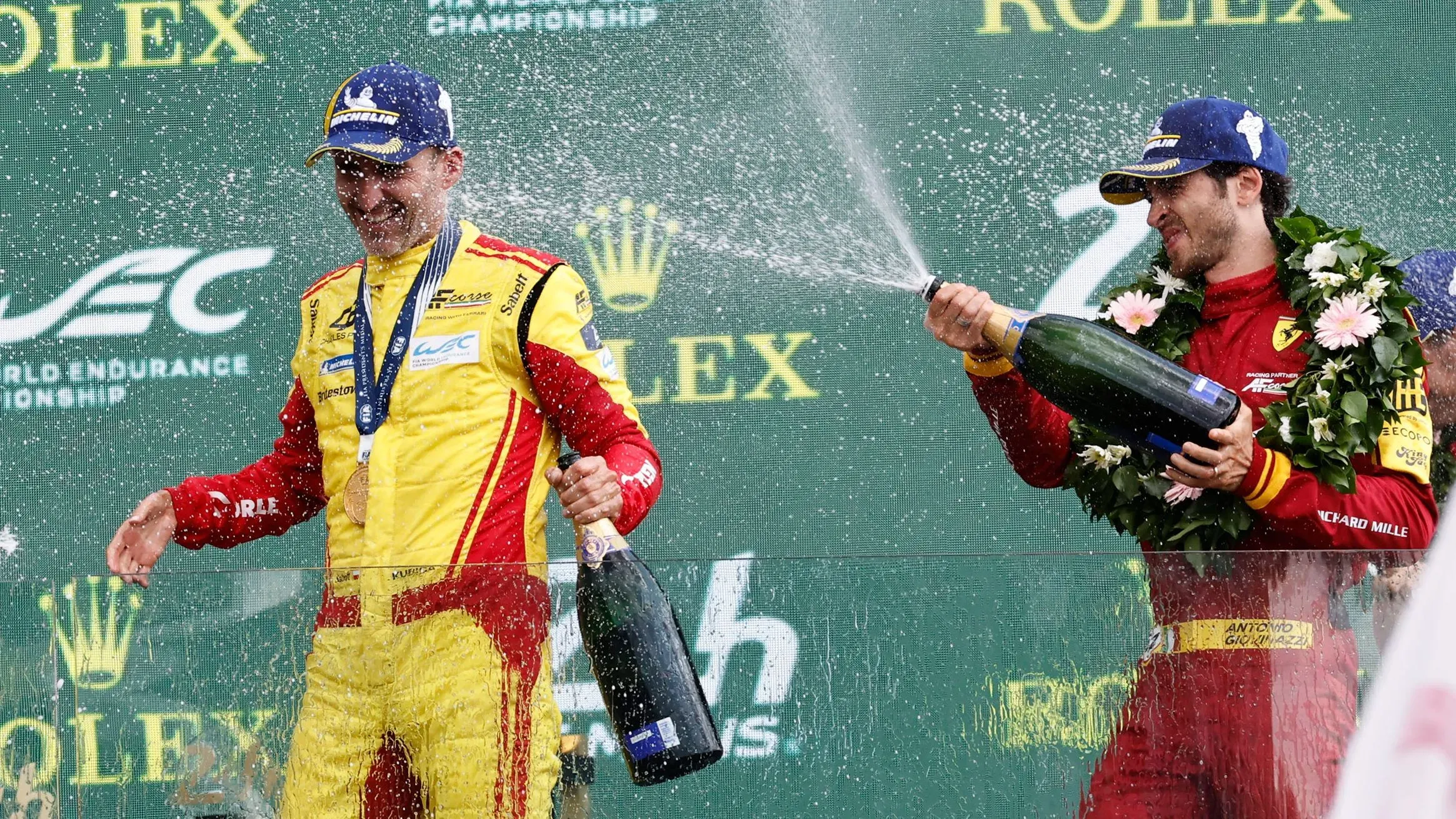 روبرت كوبيكا يحتفل بفوزه في سباق لومان 24 ساعة، محاطًا بزملائه في الفريق، مع زجاجة شامبانيا وميدالية، يعكس نجاحه في العودة إلى سباقات التحمل.