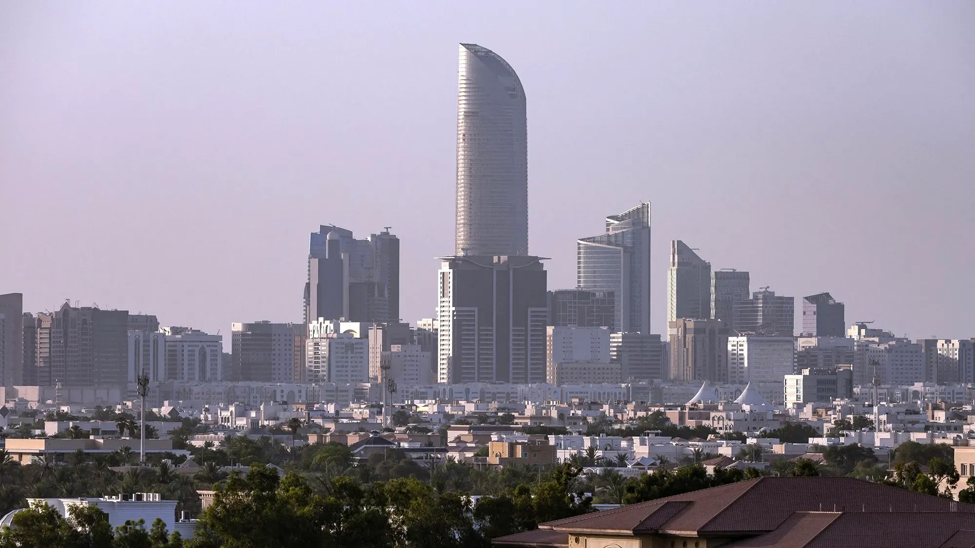 أفق مدينة أبوظبي يظهر فيه ناطحات السحاب الحديثة، مع التركيز على برج مميز، مما يعكس تطور البنية التحتية للذكاء الاصطناعي في الإمارات.