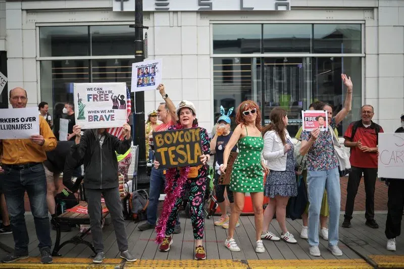 محتجون يتظاهرون خارج صالة عرض تسلا، يحملون لافتات تدعو لمقاطعة الشركة، في إطار حركة "Tesla Takedown" ضد إيلون ماسك.