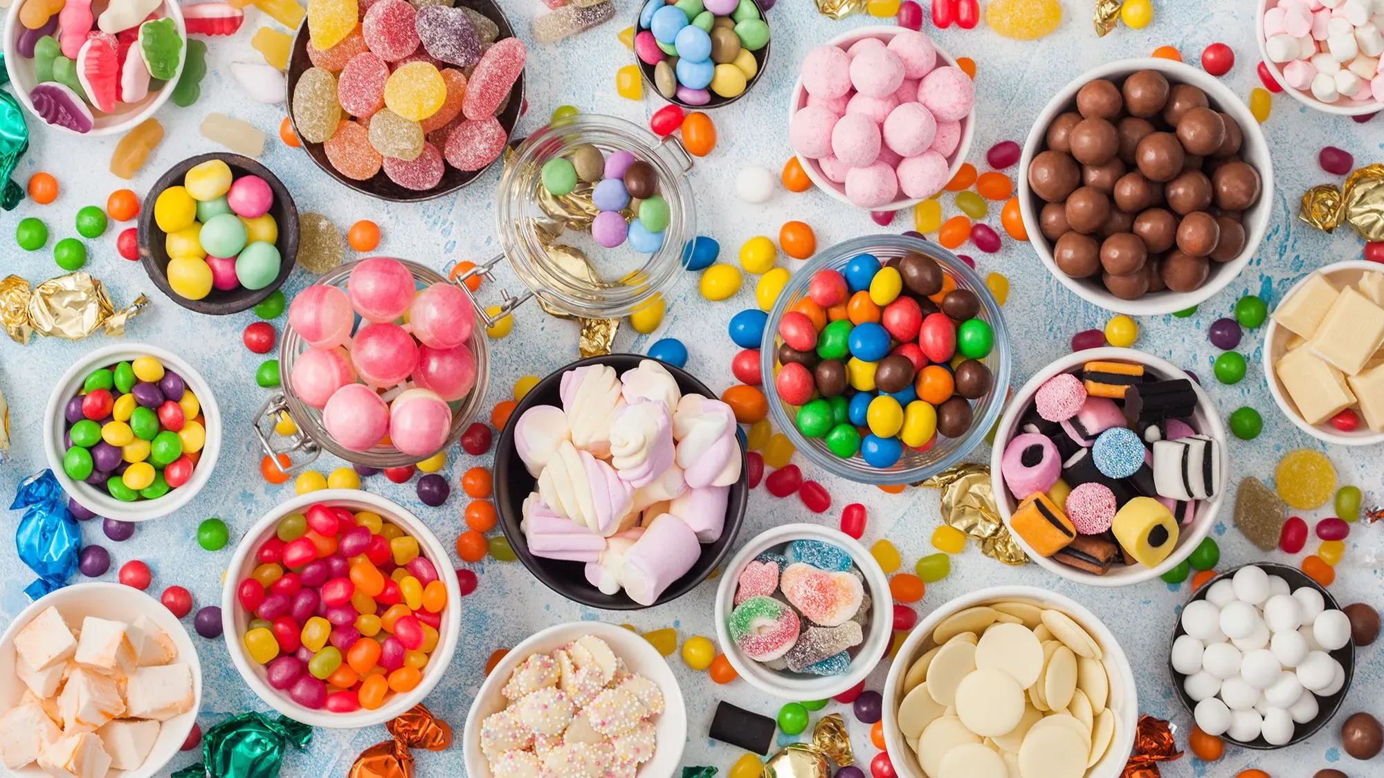 تشكيلة ملونة من الحلويات والأطعمة المزينة بأصباغ صناعية، تعكس القلق حول تأثيرها على صحة الأطفال وسلوكهم.