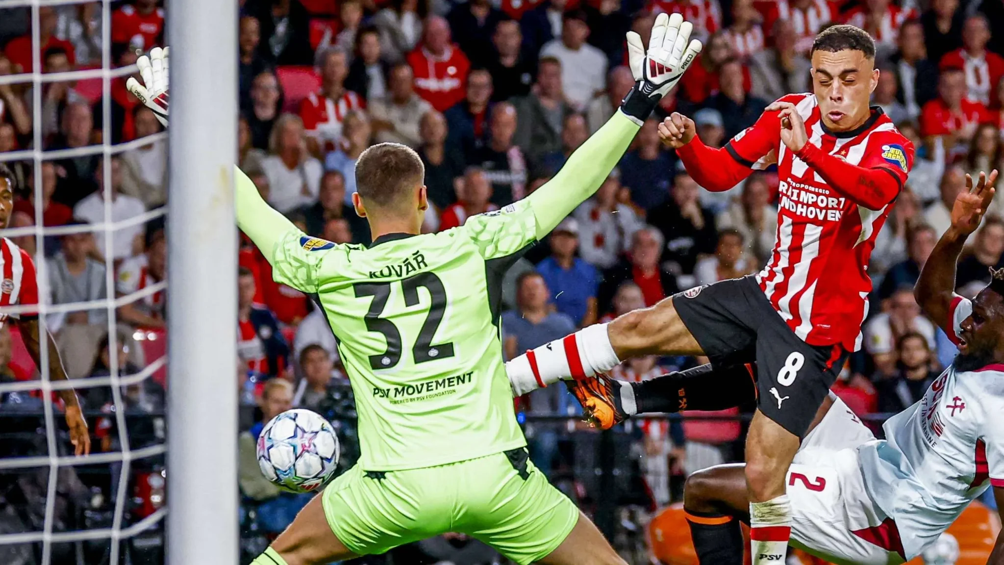 مهاجم PSV إيندهوفن يسدد كرة نحو حارس شاختار دونيتسك في دوري أبطال أوروبا وسط ضغط دفاعي مكثف.