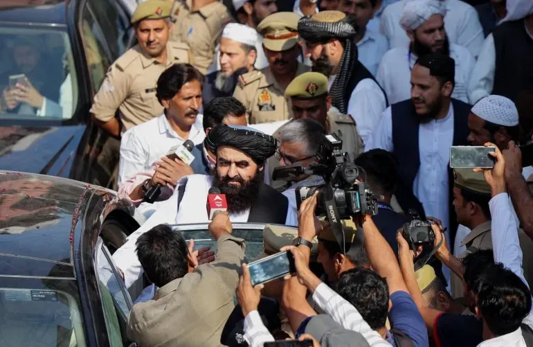 مظاهرة حاشدة في كابول، حيث يتجمع رجال ونساء حول شخصية بارزة، وسط تواجد أمني مكثف ووسائل إعلام تغطي الحدث.