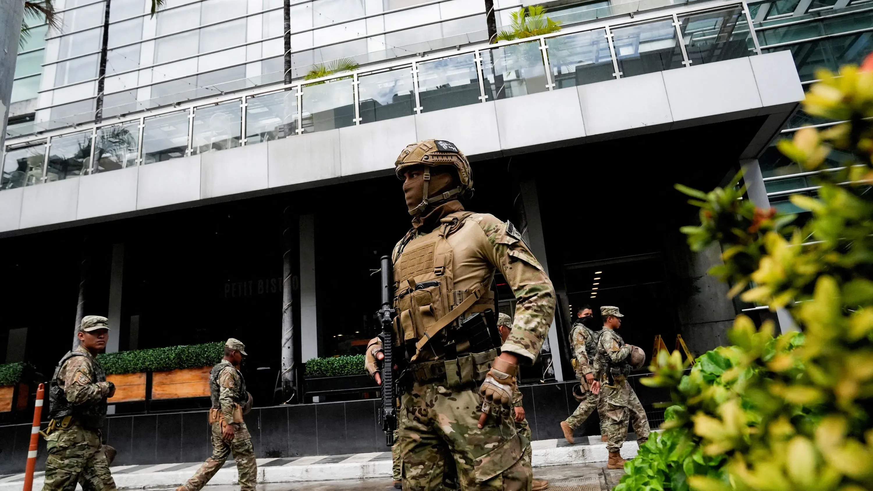 وجود جنود مسلحين يرتدون زيًا عسكريًا في شارع بالقرب من مبنى حكومي في بنما، مما يعكس الوضع الأمني المتوتر في البلاد.