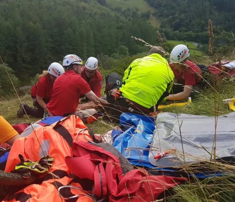 فريق إنقاذ يقدم المساعدة لدارين إدواردز بعد تعرضه لحادث تسلق خطير في شمال ويلز، محاط بمعدات الطوارئ في منطقة جبلية.