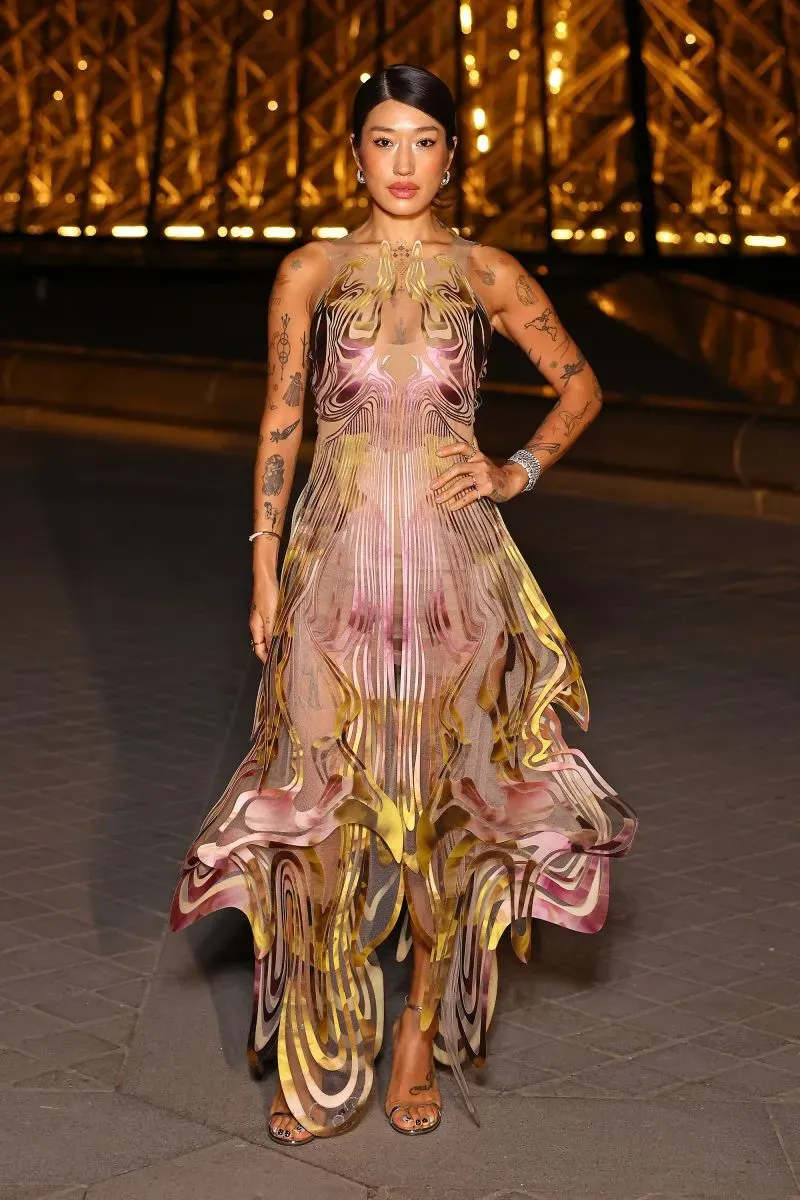 عارضة أزياء ترتدي فستانًا ملونًا بتصميم متداخل، تظهر أمام متحف اللوفر في باريس خلال أسبوع الموضة.