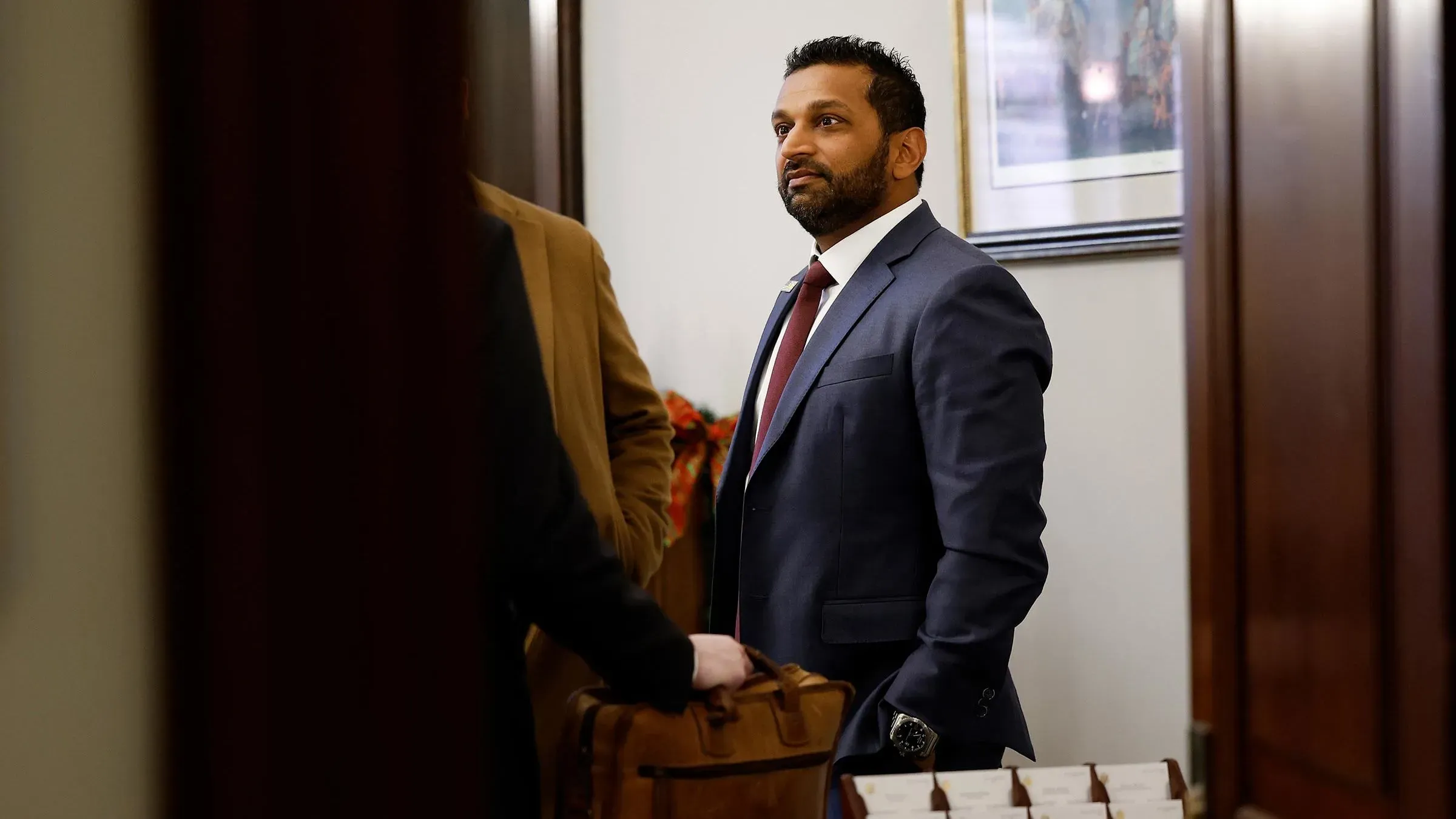 شخص يرتدي بدلة رسمية، يقف داخل مكتب يحمل حقيبة، يظهر قلقه قبل التحولات السياسية المرتقبة وتأثيرها عليه وعائلته.