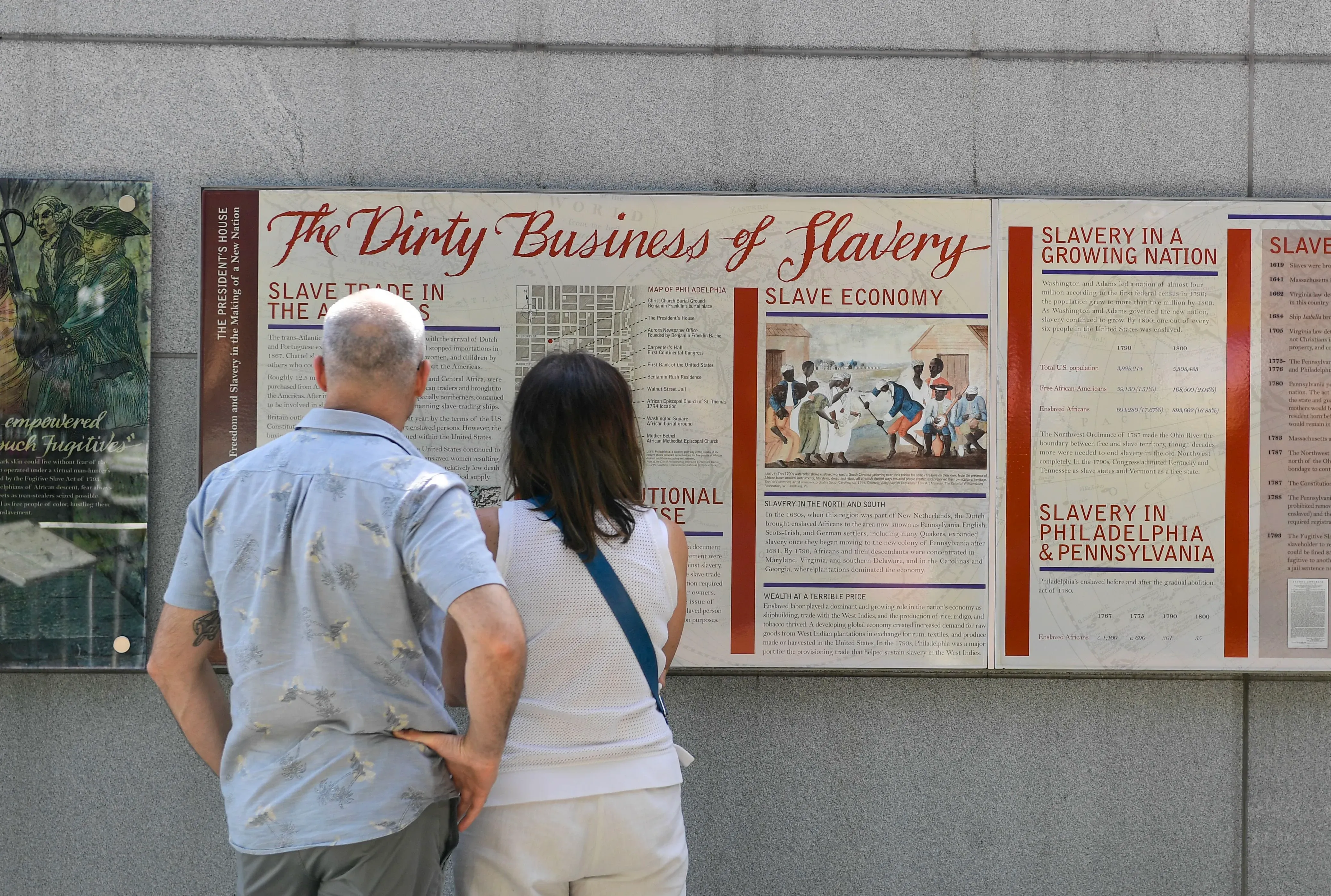 زوار يتأملون لوحات عرض تتحدث عن العبودية في متنزه الاستقلال التاريخي بفيلادلفيا، وسط دعوى قضائية لإعادة المعرض.