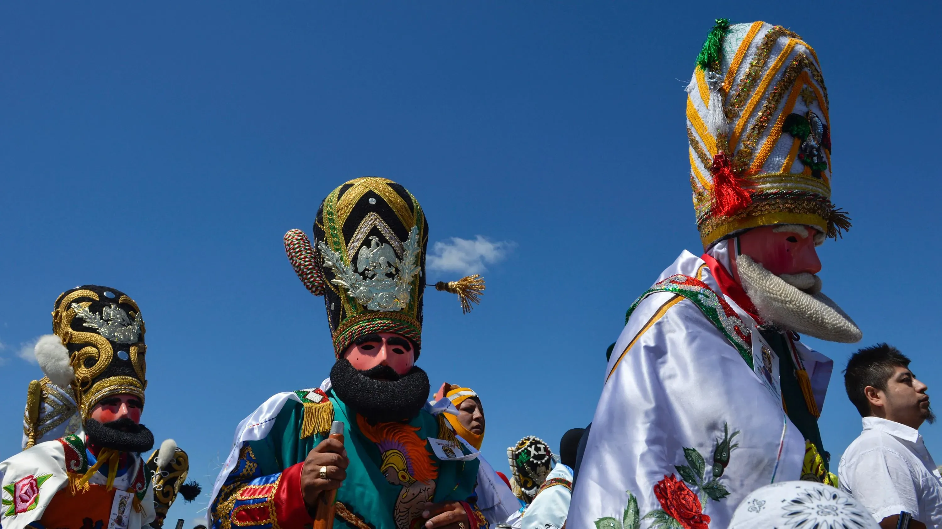 شخصيات ملونة ترتدي أزياء تقليدية وقبعات مزخرفة، تعكس الثقافة المكسيكية، خلال الاحتفالات التي ألغيت بسبب مخاوف من مداهمات الهجرة.