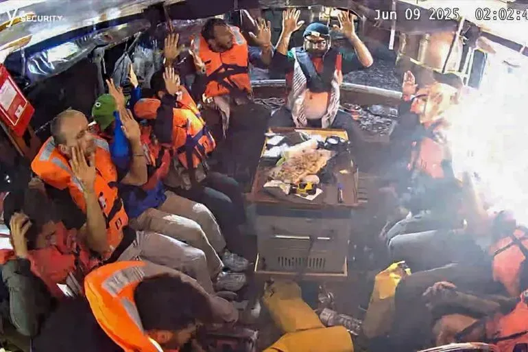 ناشطون على متن سفينة "مدلين" يرتدون سترات نجاة، يظهرون في حالة من القلق بعد اعتراضهم من قبل القوات الإسرائيلية في المياه الدولية.