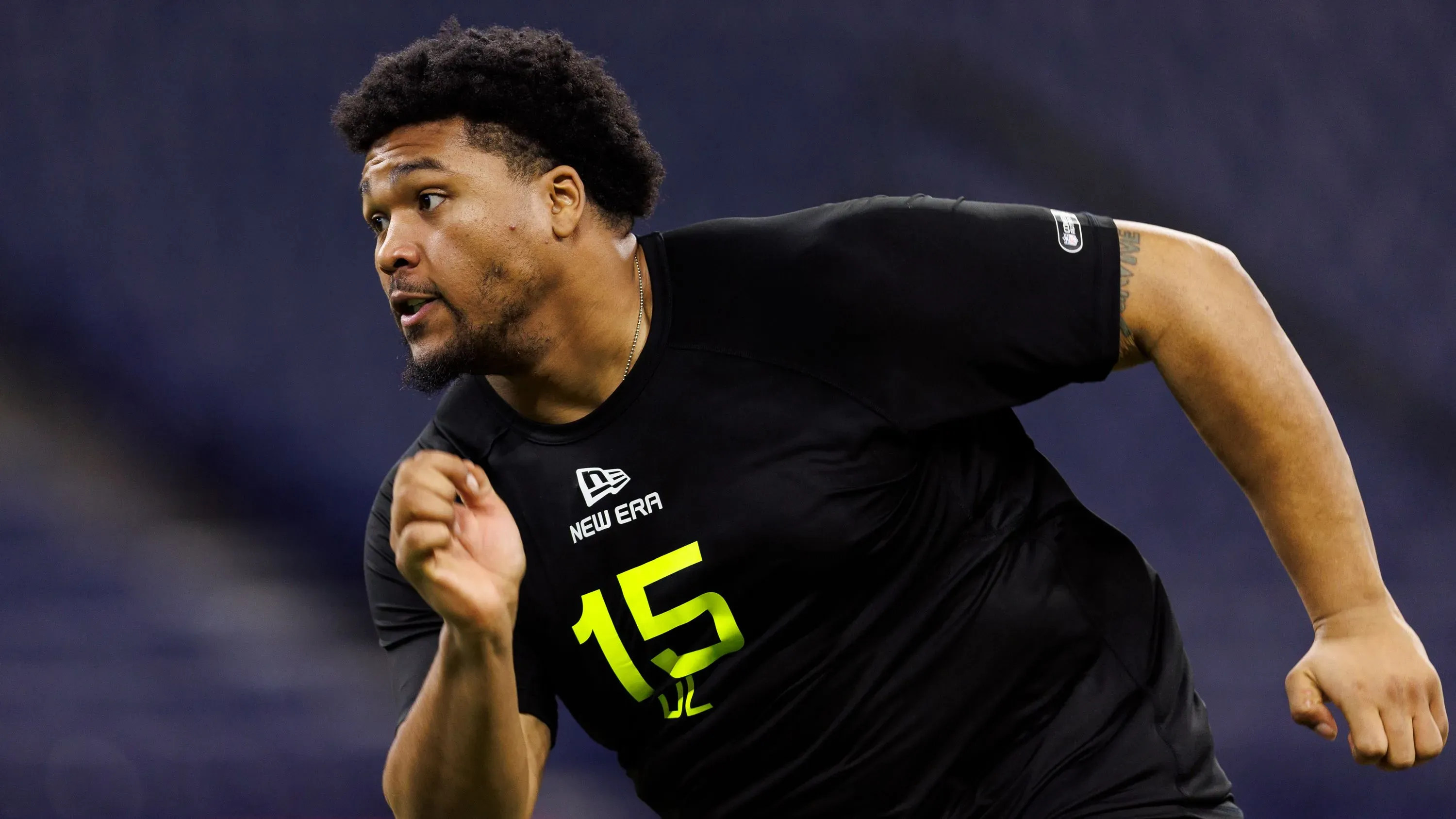 ديريك هارمون، لاعب كرة قدم، يتدرب بجد في ملعب، مع التركيز على أدائه بعد اختياره في مسودة دوري كرة القدم الأمريكية.