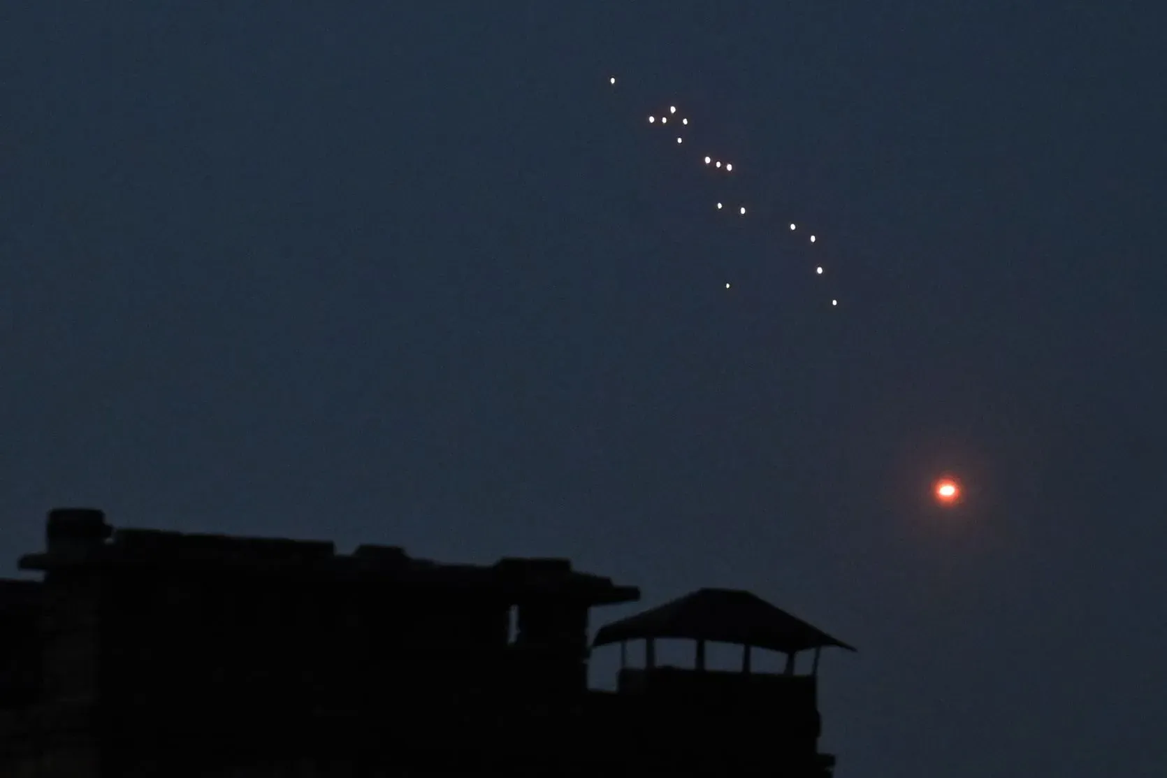 أضواء متوهجة تظهر في سماء الليل، تشير إلى هجوم جوي روسي على أوكرانيا، مع وجود مبنى في المقدمة.