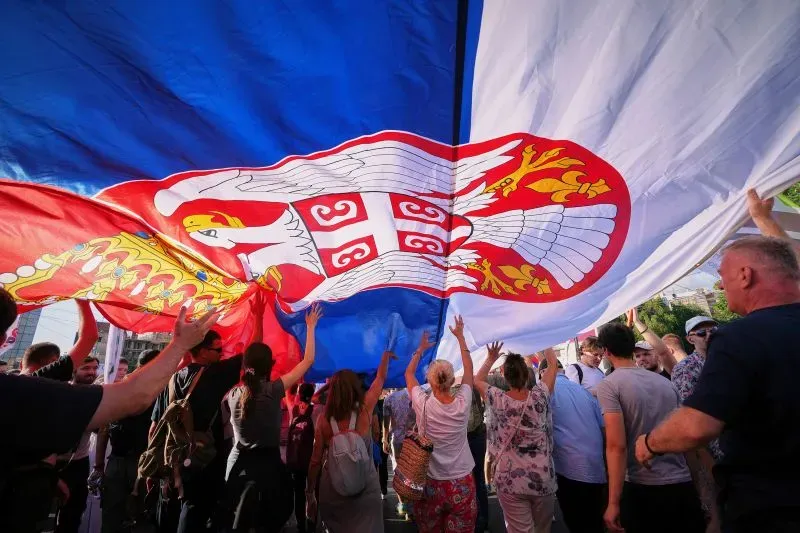 محتجون يحملون علم صربيا الكبير خلال مظاهرة في بلغراد ضد الحكومة، مطالبين بإجراء انتخابات برلمانية مبكرة.