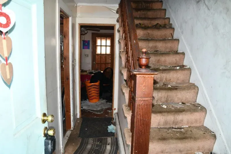 مدخل منزل في واتربري، كونيتيكت، يظهر سلالم متسخة وأثاث مبعثر، مما يعكس ظروف الحياة القاسية التي عاشها الرجل المحتجز.