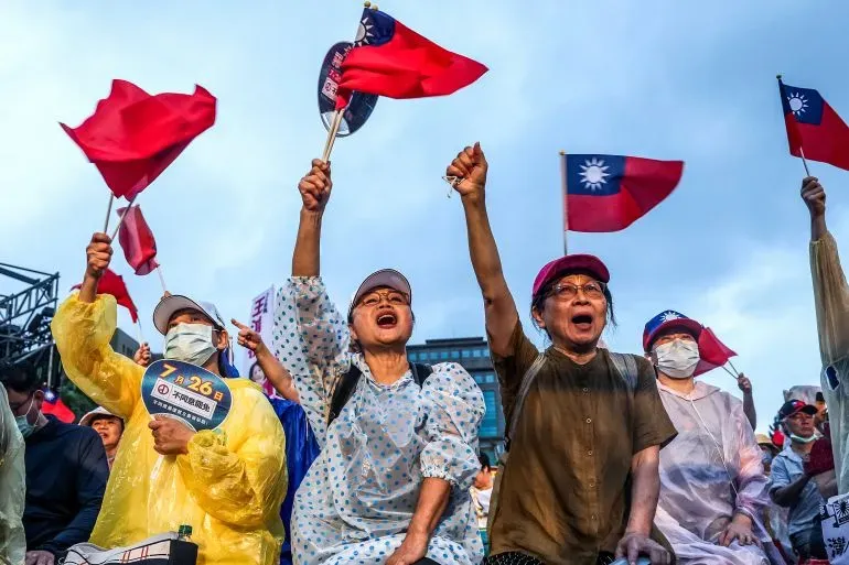 محتجون يحملون أعلام تايوانية ويرفعون أصواتهم خلال تجمع انتخابي، معبرين عن دعمهم للحزب الديمقراطي التقدمي.
