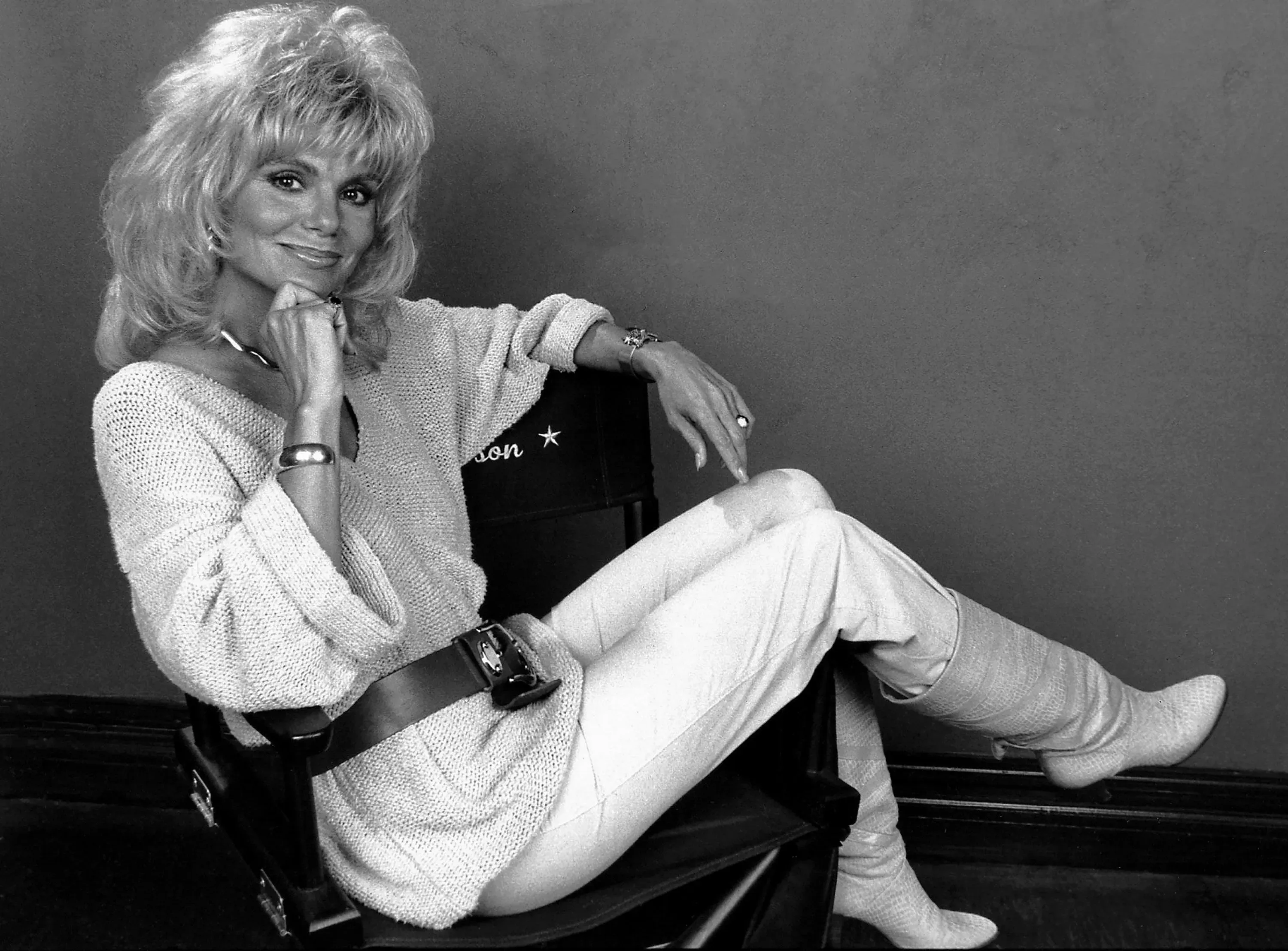 تظهر الصورة لوني أندرسون، ممثلة مشهورة، جالسة على كرسي مع ابتسامة، مرتدية ملابس أنيقة تعكس أسلوبها المميز في مسلسل "WKRP in Cincinnati".