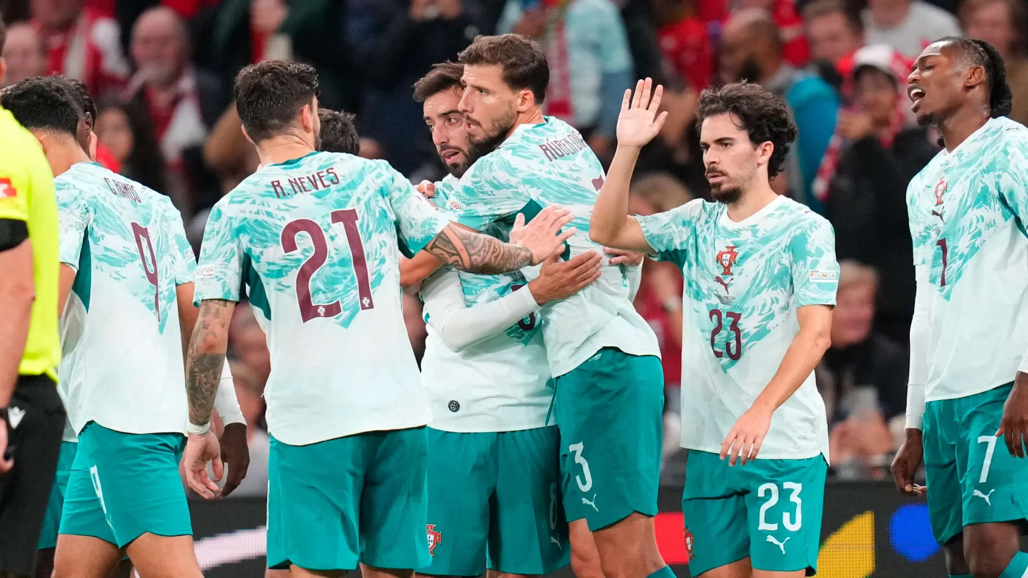 لاعبو منتخب البرتغال يحتفلون بهدف في مباراة حاسمة ضد الدنمارك ضمن دوري الأمم الأوروبية، مع أجواء حماسية في الملعب.