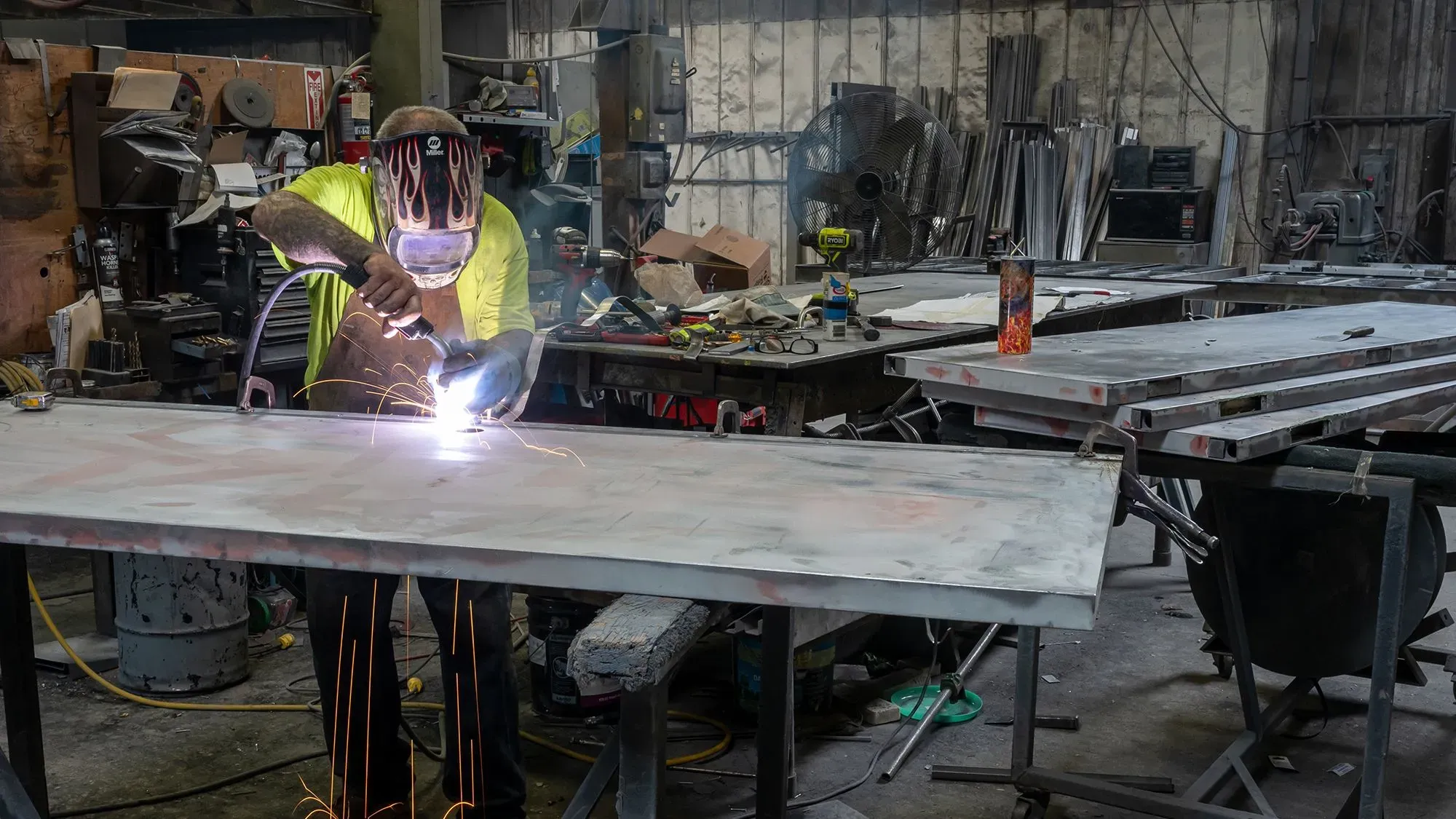 عامل يقوم باللحام في ورشة عمل، حيث تظهر الشرارات أثناء العمل، مما يعكس نشاط التوظيف في قطاع السلع.