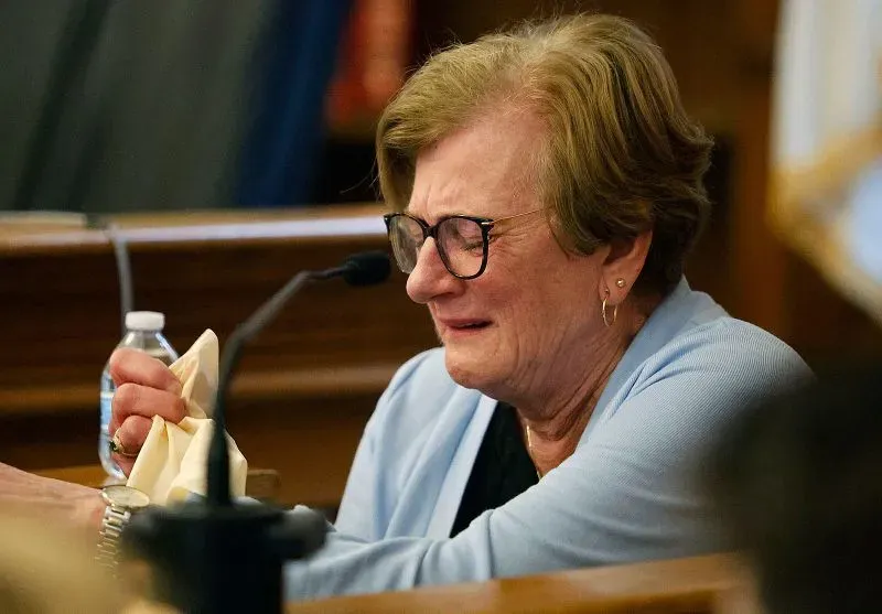 امرأة مسنّة تبكي في قاعة المحكمة، ممسكةً بمنديل، تعبيرها يعكس مشاعر الحزن والتوتر خلال محاكمة كارين ريد.