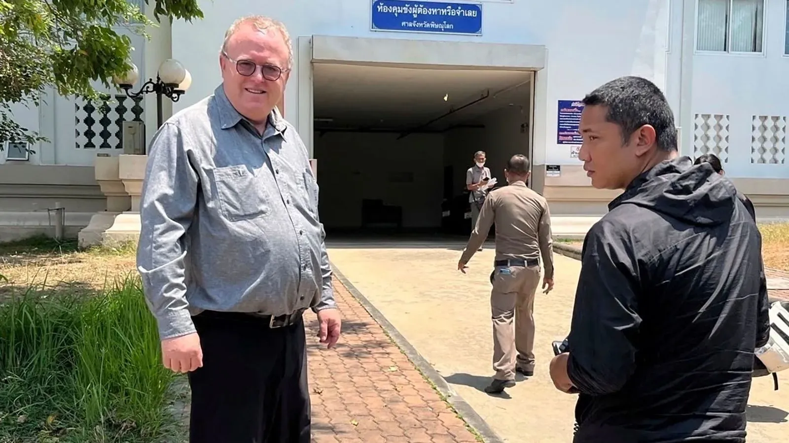 أكاديمي أمريكي، بول تشامبرز، يقف خارج مبنى حكومي في تايلاند بعد إطلاق سراحه بكفالة، وسط قلق بشأن حرية التعبير.