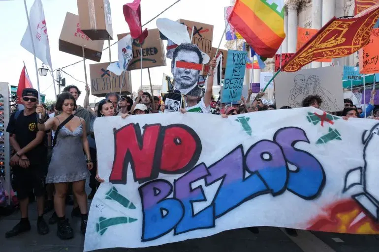 محتجون في مدينة البندقية يحملون لافتات معارضة لجيف بيزوس خلال مسيرة احتجاجية، تعبيرًا عن غضبهم من تأثيره على المدينة.