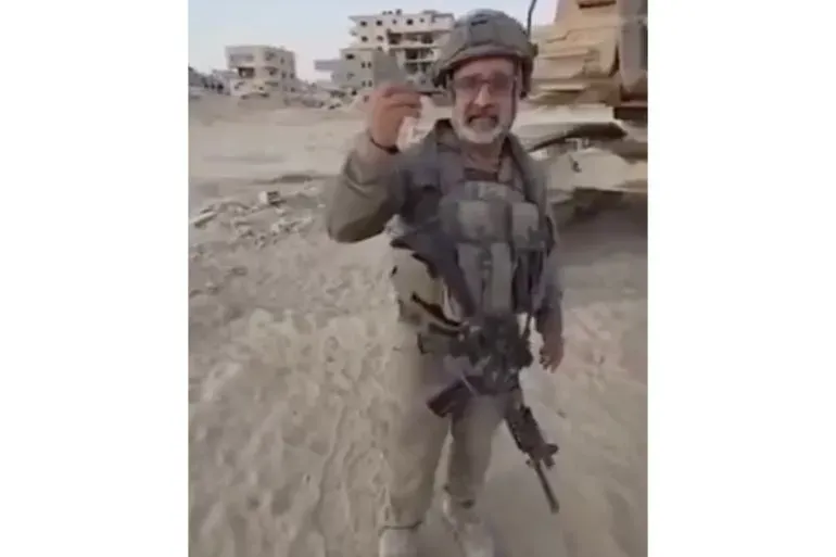 رجل يرتدي زيًا عسكريًا ويحمل شيئًا بيده، يقف في منطقة مدمرة، مع خلفية من المباني المهدمة، مما يعكس آثار النزاع في غزة.