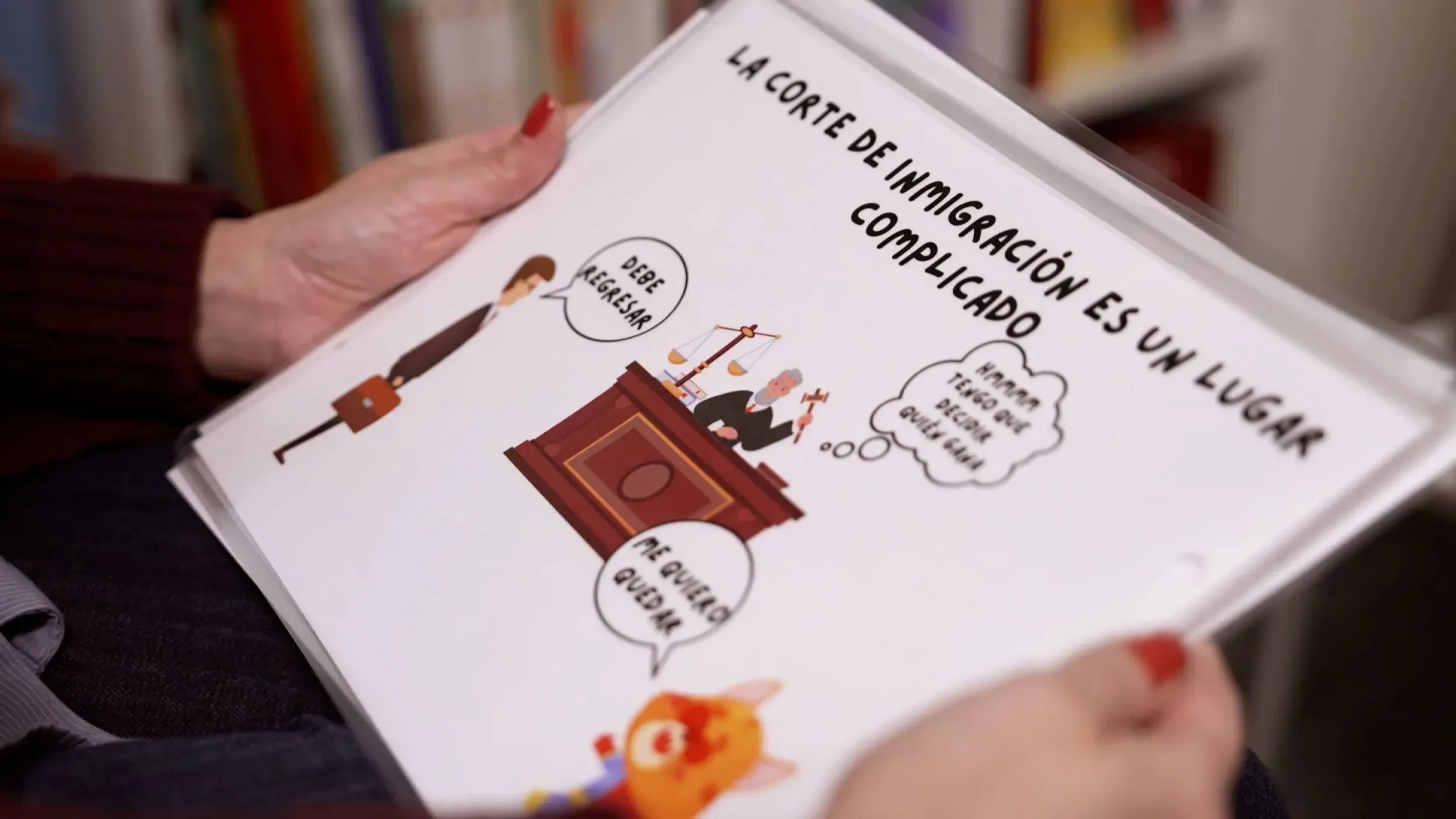 كتيب ملون يشرح للأطفال كيفية التعامل مع نظام الهجرة، يظهر قاضيًا ومحاميًا وقطًا كرتونيًا. يركز على أهمية الدعم القانوني للأطفال المهاجرين.