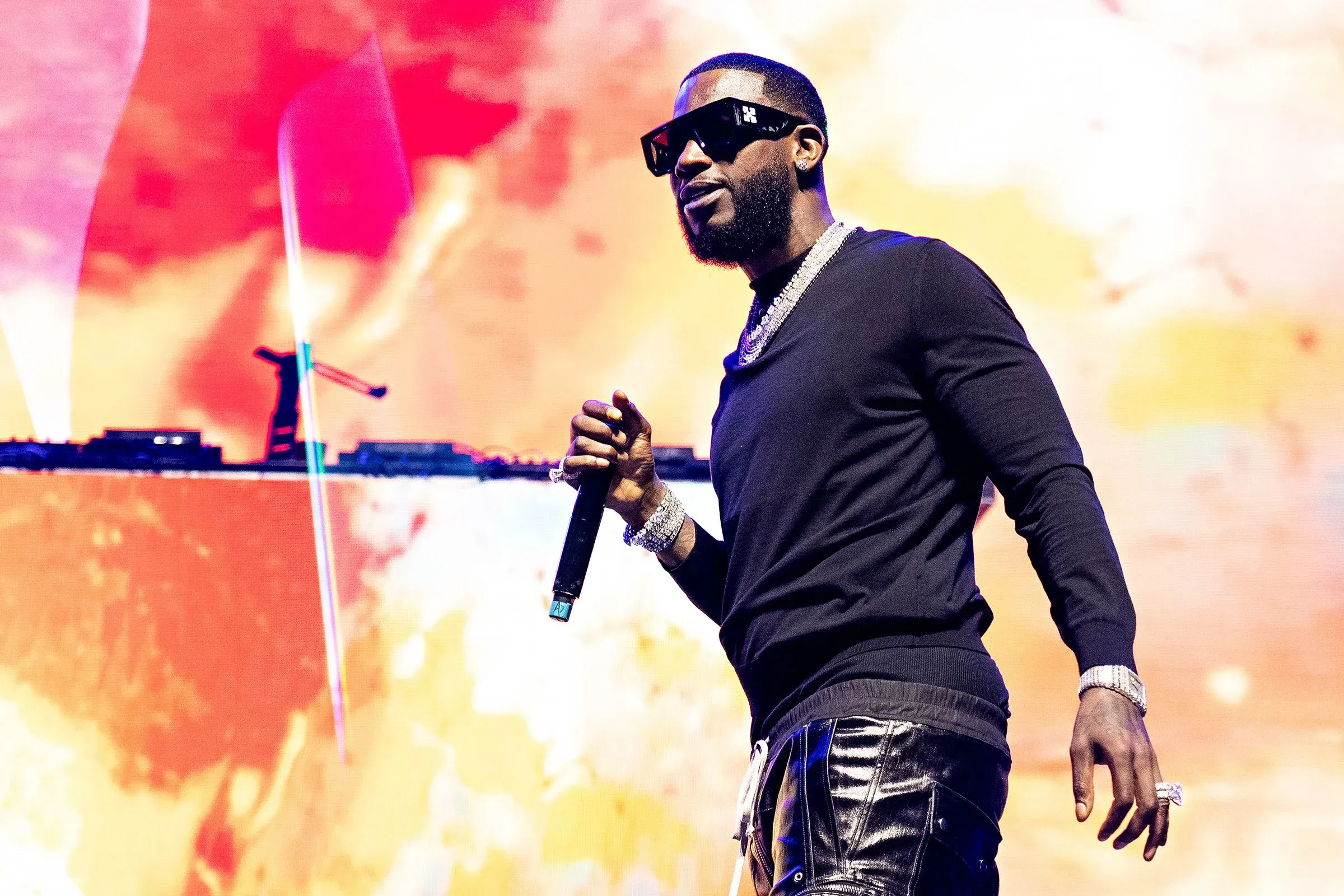 مغني الراب بوه شيستي يؤدي على المسرح، مرتديًا نظارات شمسية، وسط أضواء ملونة، في سياق حديث عن قضايا قانونية تتعلق بالعنف.