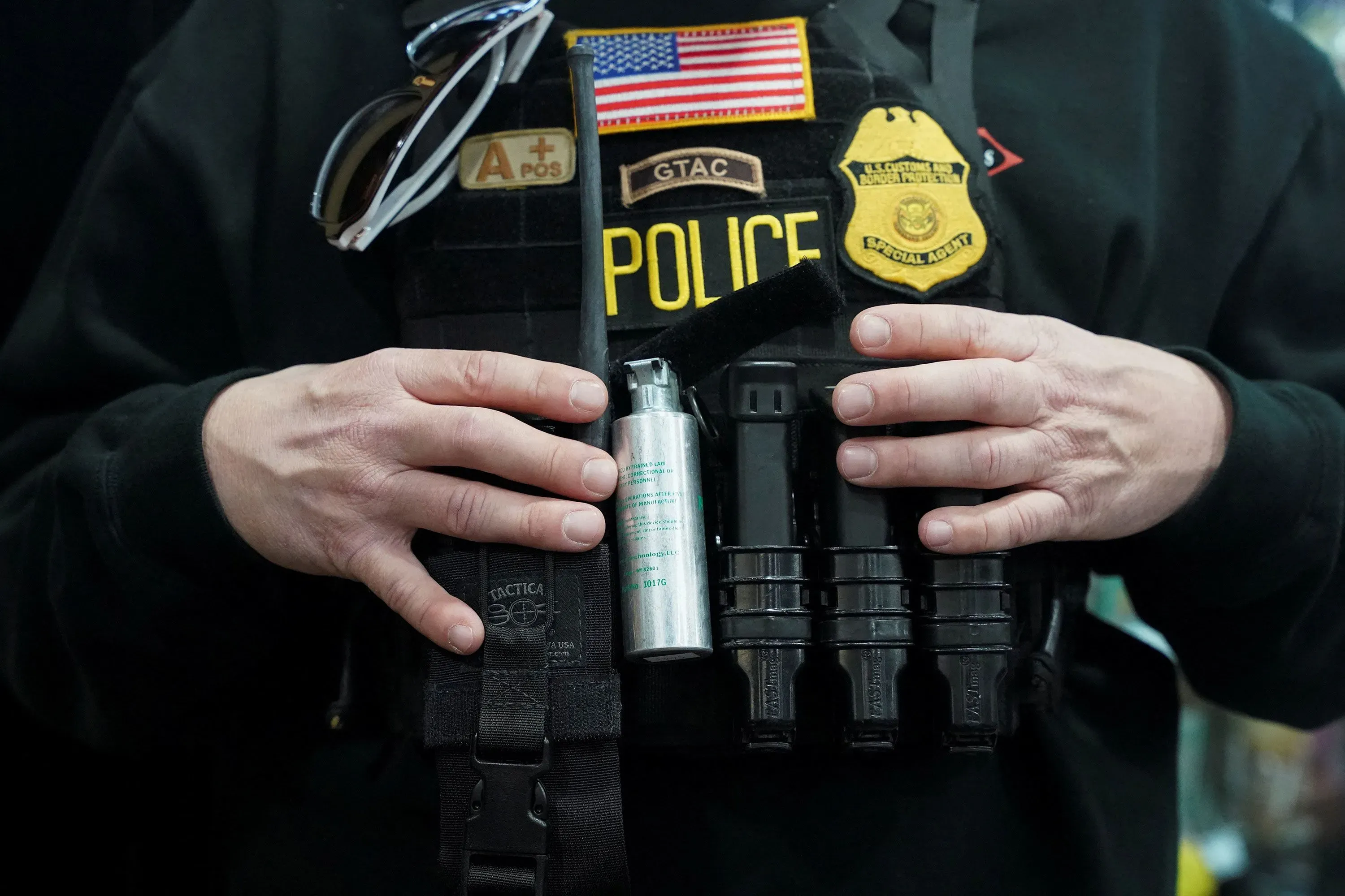 شرطي يحمل معدات إنفاذ القانون، بما في ذلك رذاذ الفلفل، في سياق مراقبة عمليات اعتقال المهاجرين في نيو أورليانز.