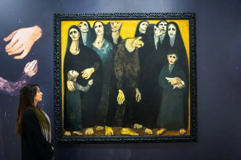 امرأة تنظر إلى لوحة فنية تعبر عن مشاعر الحزن، ضمن معرض للفن التشكيلي في مزاد سوذبيز في السعودية.