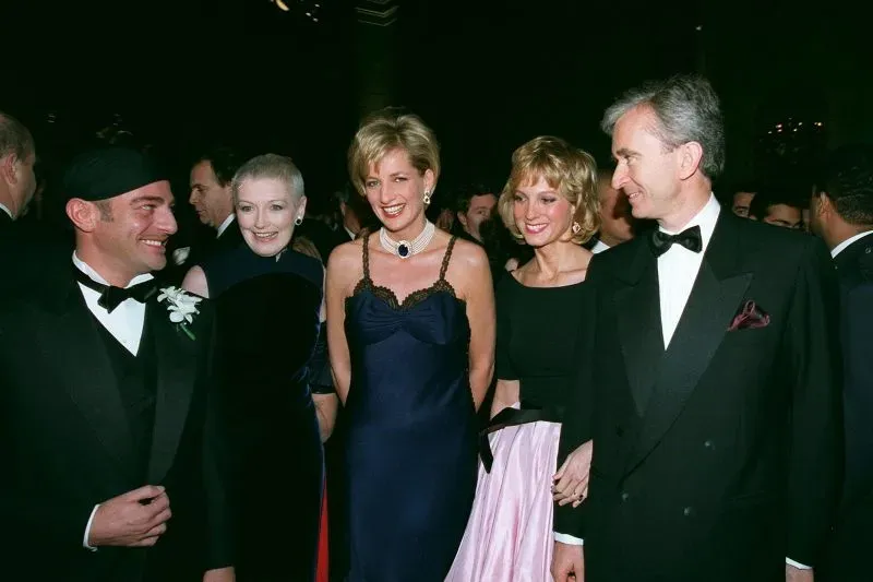 الأميرة ديانا في حفل الميت غالا عام 1996، ترتدي فستاناً جريئاً من تصميم جون غاليانو، محاطة بأصدقاء، تعكس إطلالتها تحررها من القيود الملكية.