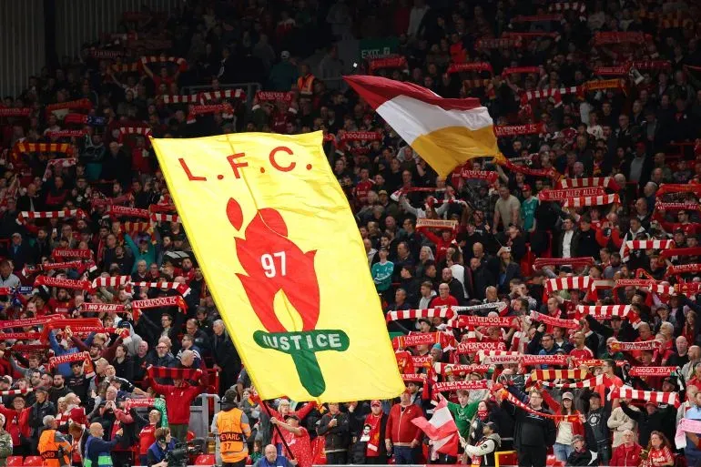 جماهير ليفربول تحمل لافتة كبيرة مكتوب عليها "L.F.C 97 JUSTICE" مع الأوشحة الحمراء، تعبيرًا عن المطالبة بالعدالة لضحايا مأساة هيلزبره.