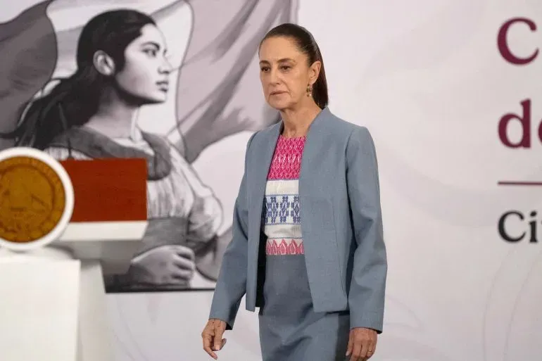 الرئيسة المكسيكية كلوديا شينباوم تسير في مؤتمر صحفي، مع خلفية تشير إلى القضايا الوطنية المتعلقة بالسيادة ومكافحة المخدرات.