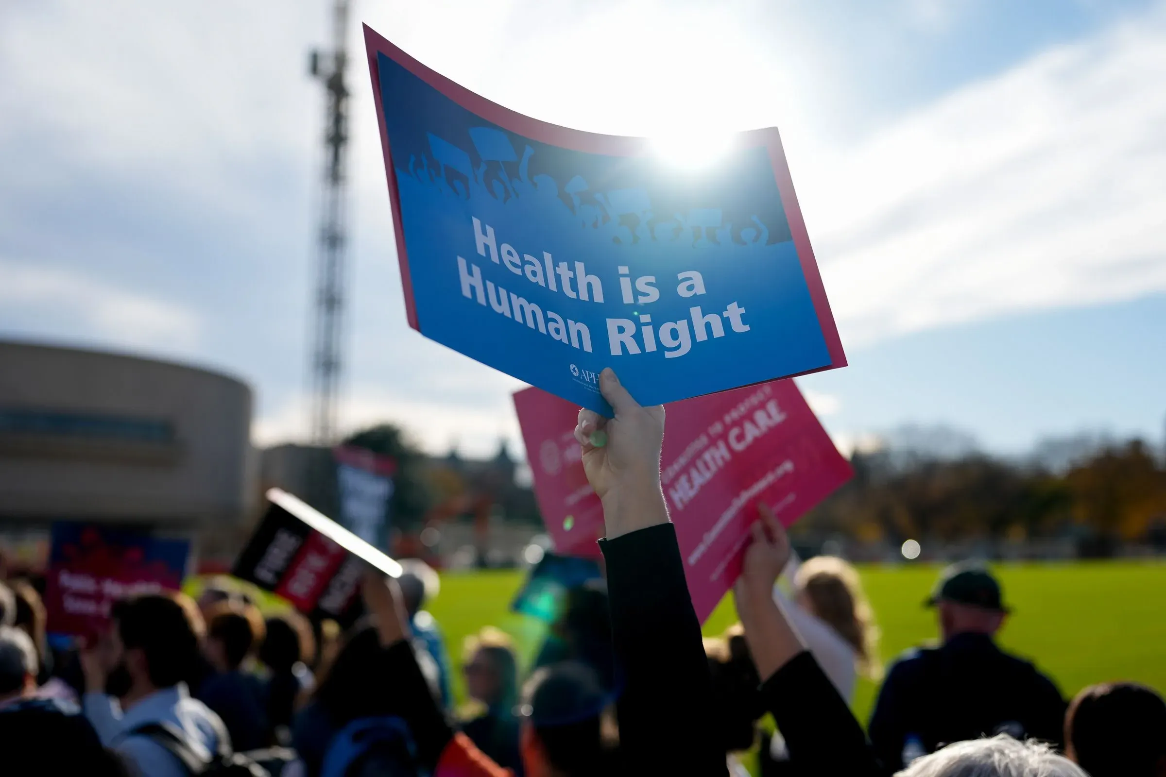 لافتة تحمل عبارة "الصحة حق إنساني" في تظاهرة لدعم الرعاية الصحية، مع أشخاص في الخلفية.