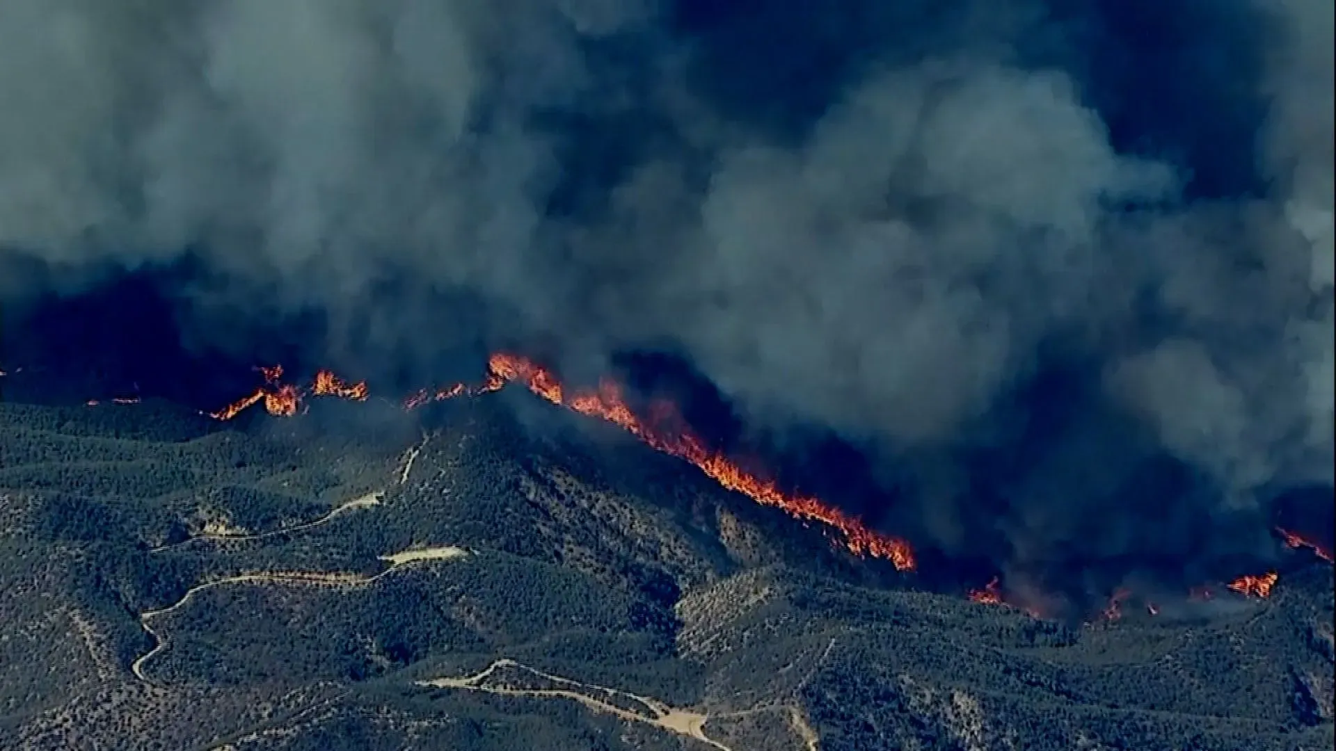 هيوز المشتعل بالقرب من بحيرة كاستايك، حيث تشتعل النيران في التلال وتظهر سحب من الدخان الكثيف تتجه نحو الطريق السريع 5.